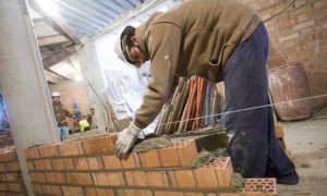 Un treballador de la construcció aixecant una paret | Adrià Costa